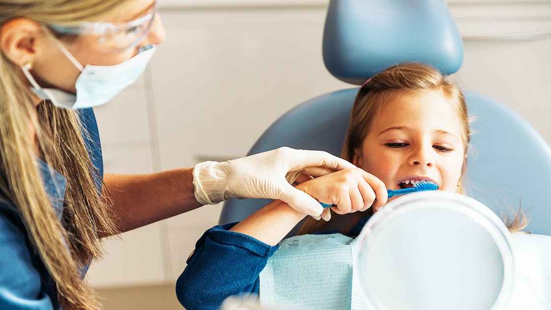 Assistant Teaching Child to Brush